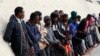 FILE - Migrants stand after being brought to shore by a Libyan coast guard at the Mediterranean Sea, in Garaboli Libya, Oct. 18, 2021.