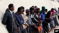 FILE - Migrants stand after being brought to shore by a Libyan coast guard at the Mediterranean Sea, in Garaboli Libya, Oct. 18, 2021.
