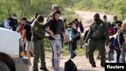 Migrantes que buscan asilo, en su mayoría de Venezuela y Cuba, son procesados por agentes de Aduanas y Protección Fronteriza después de cruzar el río Grande hacia EEUU desde México en Eagle Pass, Texas, el 13 de julio de 2022. REUTERS/Go Nakamura