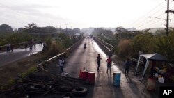 Una barricada colocada por personas que protestan contra la inflación, especialmente el aumento de los precios del combustible, obliga a la gente a caminar en Pacora, Panamá, la madrugada del 20 de julio de 2022.