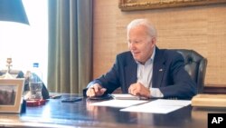 In this image provided by the White House, President Joe Biden speaks on the phone from the Treaty Room in the residence of the White House, July 21, 2022. Biden says he's "doing great" after testing positive for COVID-19. 