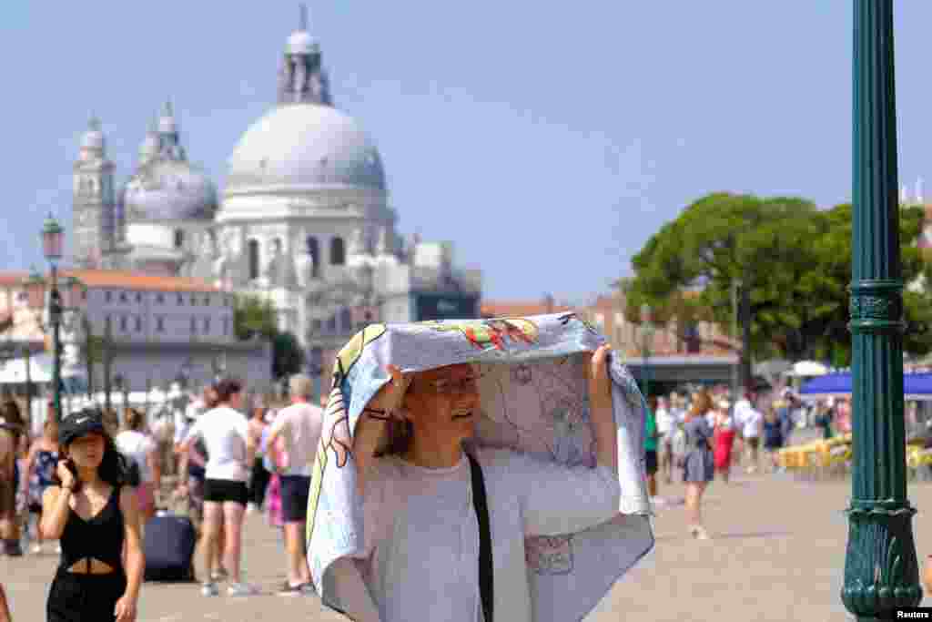 Una mujer se refresca durante las celebraciones del festival Redentore en momentos en que Venecia, Italia, se enfrenta a la segunda ola de calor del verano.