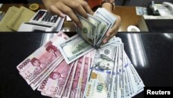 Seorang teller di money changer menghitung mata uang Rupiah dan dolar AS di Jakarta, 12 Agustus 2015. (Foto: Antara via Reuters)