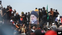 A protester holds a poster depicting Shiite cleric Muqtada al-Sadr on a bridge leading toward the Green Zone area in Baghdad, Iraq, July 30, 2022.