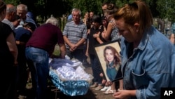 Relatives and friends of 35-year-old Anna Protsenko, who was killed in a Russian rocket attack, pray over her coffin before burial during her funeral procession, on the outskirts of Pokrovsk, eastern Ukraine, July 18, 2022.