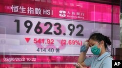 週二香港街頭，一名女子走過恆生指數顯示大跌的電子顯示牌。 （2022年8月2日）
