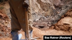 Un homme tenant une pioche observe des collègues travaillant dans un puits ouvert de la mine de coltan SMB près de la ville de Rubaya, dans l'est de la République démocratique du Congo, le 13 août 2019. Photo prise le 13 août 2019. REUTERS/Baz Ratner