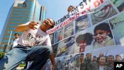 FILE - Weiming Chen, a sculptor and photographer, shows his artwork and photos of conflict in Syria during a demonstration in Los Angeles, Sept. 10, 2013. Chen is alleged to have been one of the victims of a Chinese government plot to target U.S.-based critics.