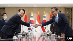 Presiden Korea Selatan Yoon Suk-yeol (kiri) berjabat tangan dengan Presiden Indonesia Joko Widodo (kanan) dalam pertemuan mereka di kantor kepresidenan di Seoul, 28 Juli 2022. (YONHAP / AFP) 