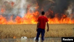 A shepherd watches a fire burning a wheat field between Tabara and Losacio during the second heatwave of the year, in the province of Zamora, Spain, July 18, 2022. REUTERS/Isabel Infantes