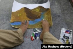 Seorang seniman sedang melukis dengan menggunakan kakiknya. (Foto: REUTERS/Ako Rasheed)