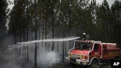 Un bombero rocía agua mientras el humo se eleva en un incendio forestal cerca de Louchats, a 35 kilómetros (22 millas) de Landiras en Gironde, suroeste de Francia, el lunes 18 de julio de 2022. (Philippe López/vía AP)