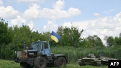 Un agricultor usa un tractor para remolcar un transporte blindado de personal abandonado por las tropas rusas y requisado por un agricultor ucraniano a fines de marzo, cerca de la aldea de Mala Rogan, región de Kharkiv, el 28 de julio de 2022.