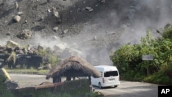 Boulders fall as a vehicle negotiates a road during an earthquake in Bauko, Mountain Province, Philippines on July 27, 2022. A strong earthquake left some people dead and injured dozens in the northern Philippines on Wednesday.