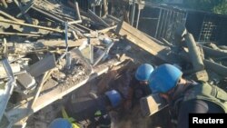 乌克兰国家紧急情况部公布的照片显示，救援人员在顿涅茨克州托列次克一座被俄军炮击摧毁的居民楼废墟中搜救幸存者。(2022年7月18日)