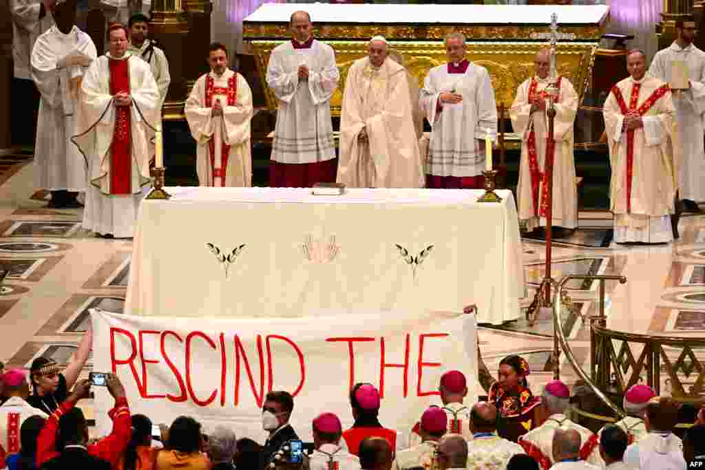Indigenous people hold a protest banner as Pope Francis celebrates Mass at the National Shrine of Sainte-Anne-de-Beaupré in Quebec, Canada.