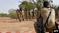 FILE: An Austrian army instructor (R) looks on as Burkinabe soldiers demonstrate techniques while taking part in a training exercise at the Kamboinsé general Bila Zagre militairy camp near Ouagadougou on April 13, 2018, during a military anti-terrorism exercise.