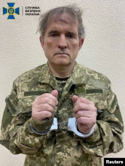 FILE - Pro-Russian Ukrainian politician Viktor Medvedchuk is seen in handcuffs while being detained by security forces in unknown location in Ukraine, in this handout picture released April 12, 2022.