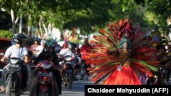 Orang-orang menonton model Aceh dalam peragaan busana jalanan selama Pekan Busana Aceh di Banda Aceh, sebagai ilustrasi. Fenomena fashion street seperti yang terjadi di Jakarta, memunculkan aktivitas serupa di sejumlah daerah di Indonesia. (Foto: AFP/CHAIDEER MAHYUDDIN)