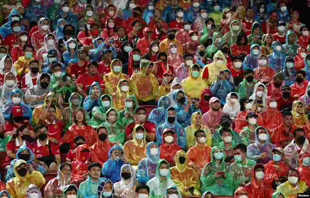 Fans wearing rain ponchos and face masks watch the Manchester United v Liverpool preseason friendly match, at Rajamangala National Stadium, Bangkok, Thailand.