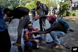 A protester helps another after police fired teargas to disperse them before they stormed Sri Lankan Prime Minister Ranil Wickremesinghe's office on July 13, 2022. (AP Photo/Eranga Jayawardena)