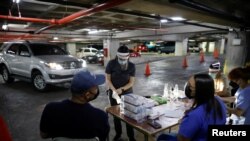 ARCHIVO - Una trabajadora de la salud se pone guantes de látex en un centro de pruebas del COVID-19 improvisado en un garaje, en Caracas, en febrero de 2022.