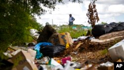 FILE - Raymond Dugas surveys a large pile of trash left across the street from his property northeast of downtown Houston on July 8, 2022.