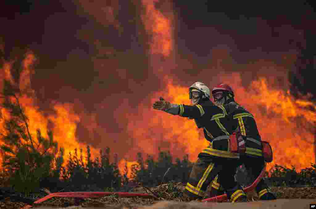 This photo provided by the fire brigade of the Gironde region (SDIS 33) shows firefighters unroll the fire hose at a forest fire at La Test-de-Buch, southwestern France, July 18, 2022.