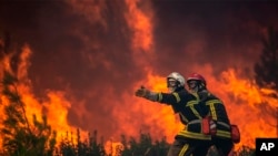 En esta foto proporcionada por el cuerpo de bomberos de la región de Gironda (SDIS 33) se muestra a los bomberos desenrollando la manguera contra incendios en un incendio forestal en La Test-de-Buch, suroeste de Francia, el lunes 18 de julio de 2022. (SDIS 33 vía AP)