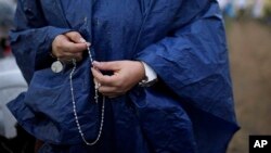 A woman holds a rosary as she waits for the start of a Mass to be celebrated by Pope Francis, in Villavicencio, Colombia, Sept. 8, 2017.