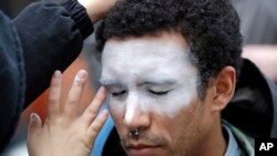 In this Oct. 31, 2018, file photo, a man, who declined to be identified, has his face painted to represent efforts to defeat facial recognition during a protest at Amazon headquarters over the company's facial recognition system, "Rekognition" in Seattle.