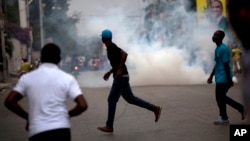 Demonstrators run from tear gas fired by police trying to disperse an anti-government protest in Port-au-Prince, Haiti, Jan. 24, 2016. Haiti was to hold a presidential and legislative runoff election on Sunday but it was put on hold indefinitely.