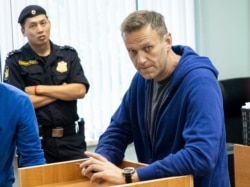 FILE - Alexei Navalny, Russia's most prominent opposition figure, who has been detained by police and charged with unlawfully organizing a public gathering, sits in a court room in Moscow, July 24, 2019.