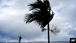 Seorang pria berdiri di atap rumahnya untuk mempersiapkan kedatangan Badai Dorian di Freeport , Grand Bahama, Bahamas, Minggu, 1 September 2019. (Foto: AP)