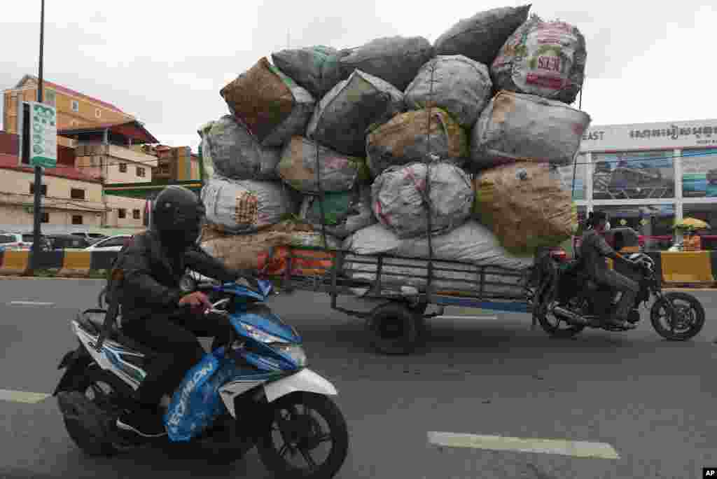 A woman, right, transports huge bags of recyclables in downtown Phnom Penh, Cambodia.
