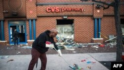  Jerald Miller helps clean up debris from a CVS pharmacy that was set on fire yesterday during rioting after the funeral of Freddie Gray, on April 28, 2015 in Baltimore, Maryland. 