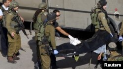 Tentara Israel membawa jenazah pria Palestina yang ditembak tewas di Hebron, Tepi Barat hari Kamis (29/10).