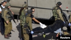 Israeli soldiers carry the body of a Palestinian, who Israeli police and army said was shot by a policeman, after he stabbed a soldier, in the West Bank old city of Hebron, Oct. 29, 2015. 