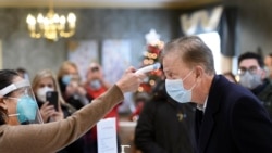 Gov. Ned Lamont has his temperature taken by Marie Cantara, left, at The Reservoir nursing facility, where the first COVID-19 vaccination was administered Friday, Dec. 18, 2020, in West Hartford, Conn