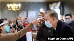 Gov. Ned Lamont has his temperature taken by Marie Cantara, left, at The Reservoir nursing facility, where the first COVID-19 vaccination was administered Friday, Dec. 18, 2020, in West Hartford, Conn