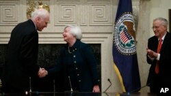 Janet Yellen estrecha la mano a Daniel K. Tarullo, luego de la juramentación. Obaseva el esposo de Yelenn, George Akerloff.