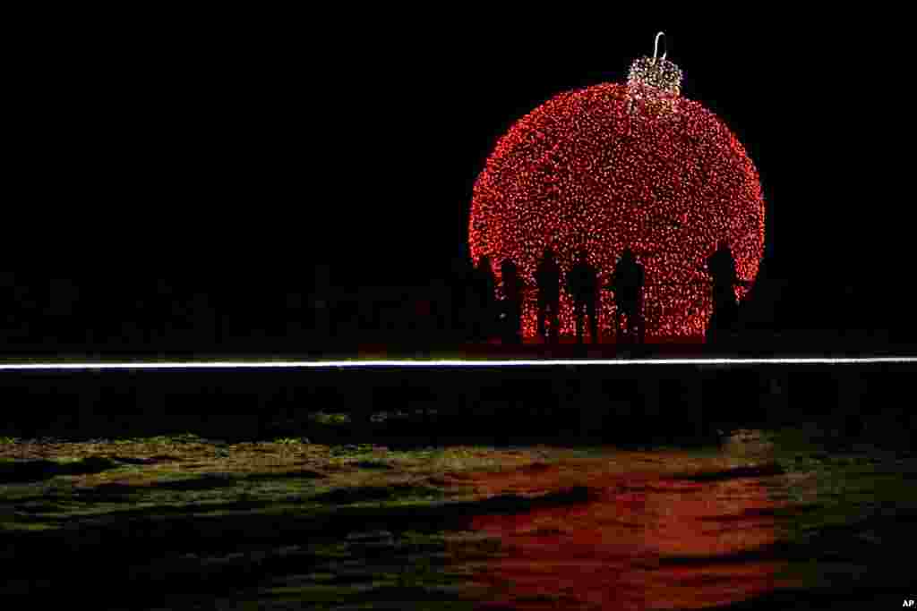 People are silhouetted on a pedestrian dock decorated with an illuminated Christmas ornament in the southern coastal city of Larnaca on the eastern Mediterranean island of Cyprus.