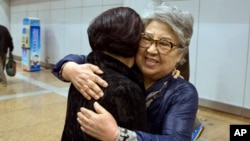 Sandra Suh (r) hugs an unidentified woman at the arrival gate of the Beijing Capital International Airport, April 9, 2015.