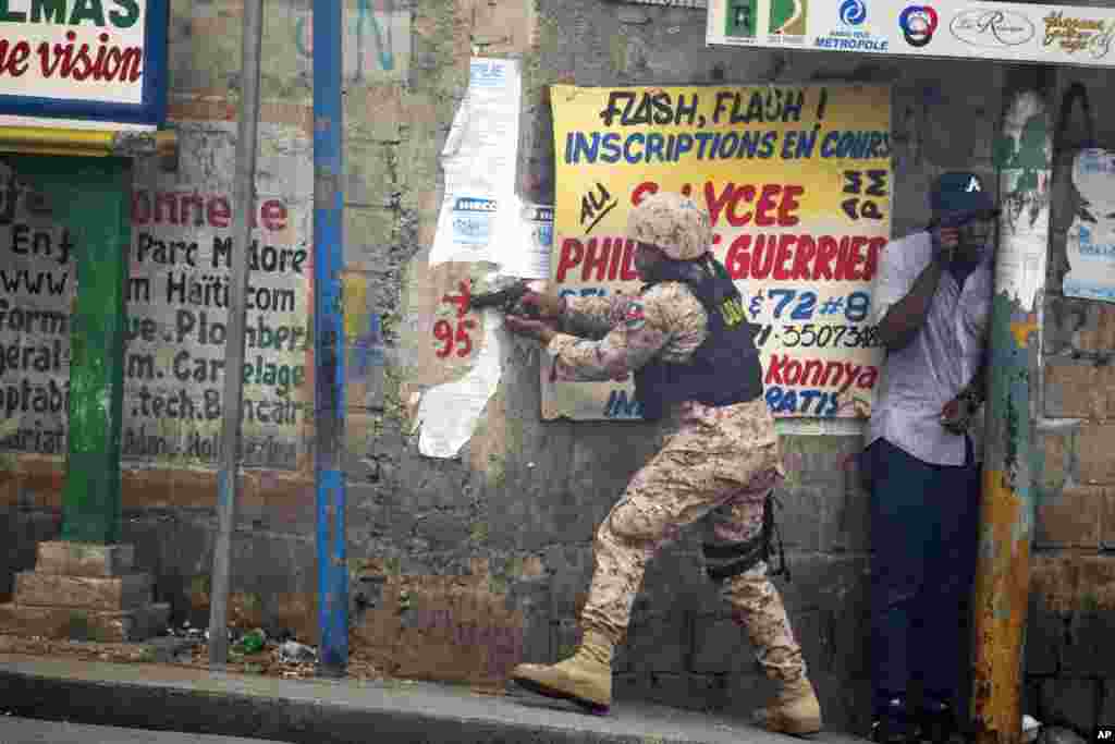 A police officer points his gun at residents of Delmas 95 district during a protest to demanding the resignation of President Jovenel Moise in Port-au-Prince, Haiti, Nov. 18, 2019.