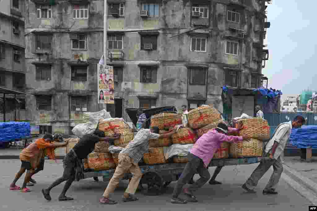 Laborers push a handcart loaded with baskets of fish from a port in Mumbai, India.