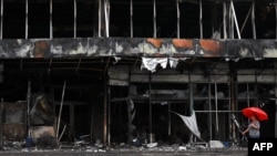 A woman carries an umbrella as she walks past a destroyed shopping mall in Bucha, in Ukraine's Kyiv region, Aug. 16, 2022. 