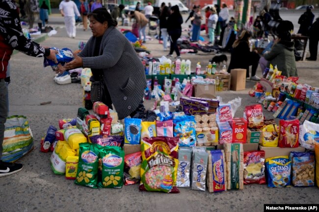 A vendor completes a transaction at a market where people can buy or barter goods, near Buenos Aires, Argentina, Aug. 10, 2022. (AP Photo/Natacha Pisarenko)