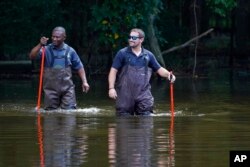 Hinds County Emergency Management Operations officials wade through flood waters as they check water levels in northeast Jackson, Miss., Aug. 29, 2022.