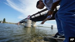 FILE: Rodolfo Laurenti, deputy director of the Remediation Consortium of the Po River, checks the salinity of the river, July 29, 2022. The amount of water entering the delta from the Po River is at an all-time low.