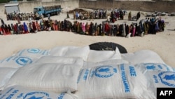 FILE - Somali people living in nearby camps queue in Mogadishu, Aug. 15, 2011, to receive cooked meals in the courtyard of a Somali no-governmental organization partnering with the World Food Program. 